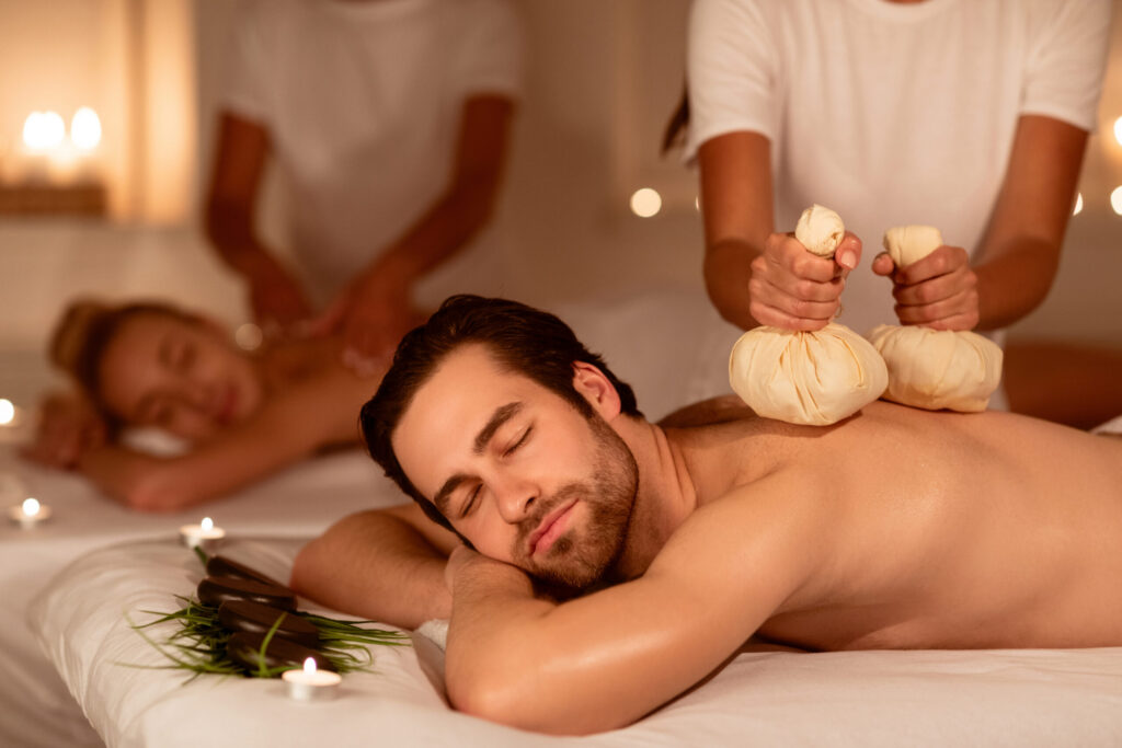 couple,relaxing,during,herbal,back,massage,with,aromatic,bags,and